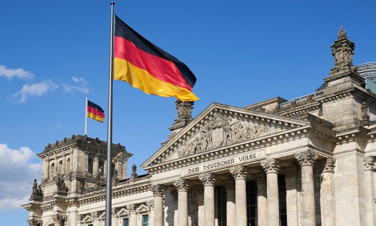 German flag over Deutscher Reichstag (Norbert Braun/Unsplash)