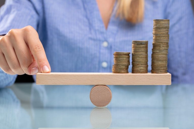 A person balances stacks of coins on primitive balance.