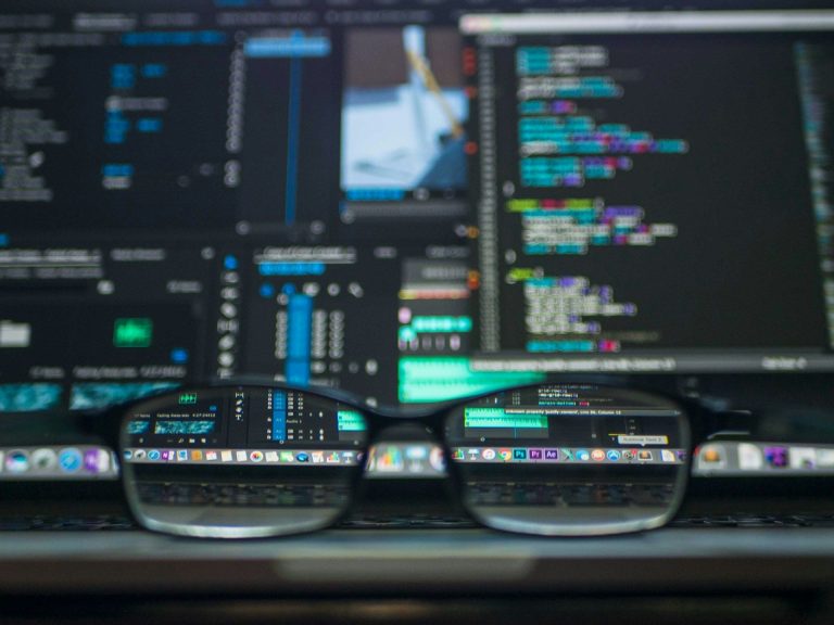 Glasses in front of monitors with code (Kevin Ku/Unsplash)